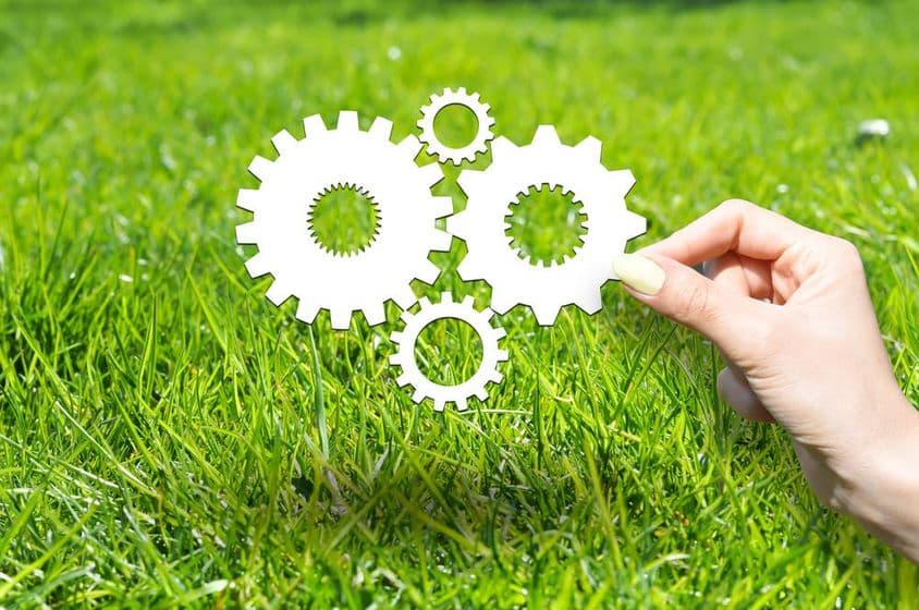 Concept with wheels and gears on green grass.