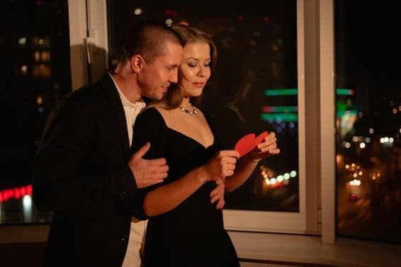 Loving couple on a Valentine's Day date, standing by the window.