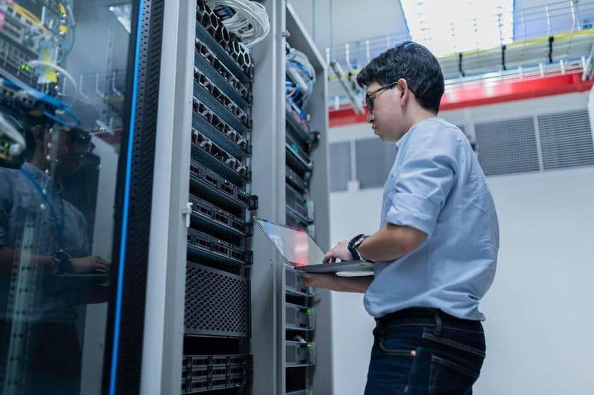 Male engineer working in a modern data center server room.