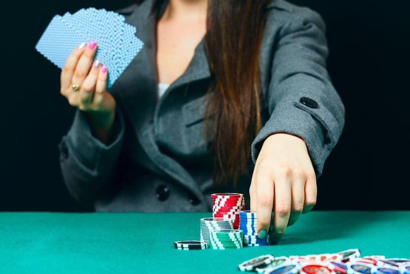 Blackjack in a casino, a woman places a bet with chips.