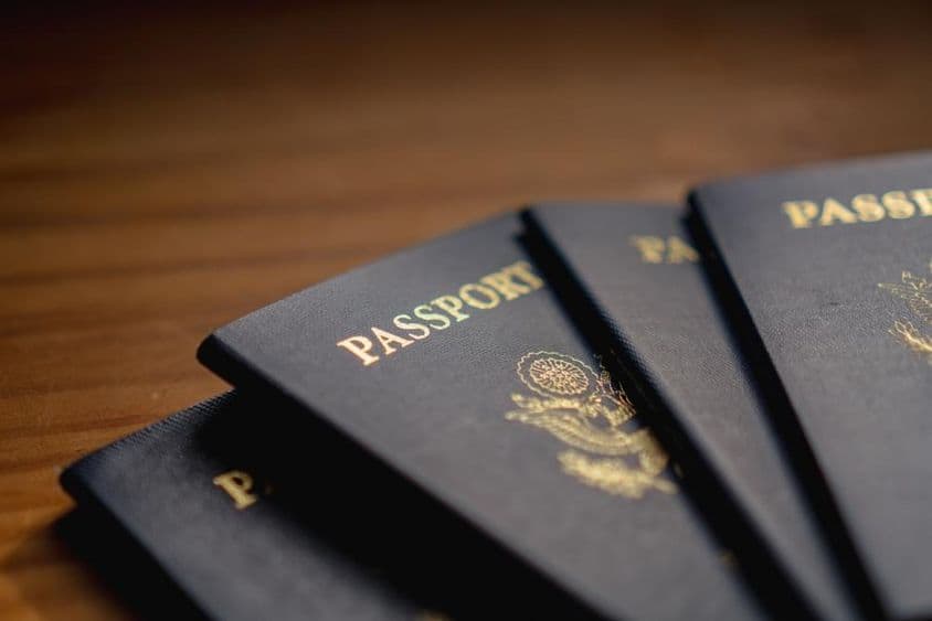 Passports stacked on a wooden table.