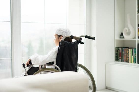A young boy in a wheelchair looking through a window.