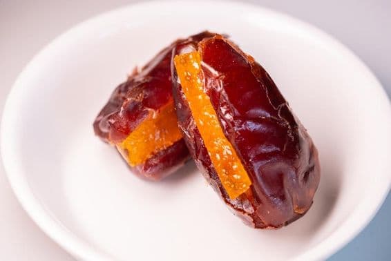 Two amazing large, fresh Dubai dates with sugared orange pieces.