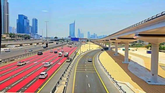 In Dubai, the road is painted red with white lane markings and speed limit signs indicating 100 km/h.
