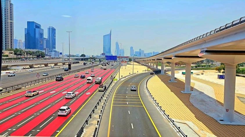 In Dubai, the road is painted red with white lane markings and speed limit signs indicating 100 km/h.