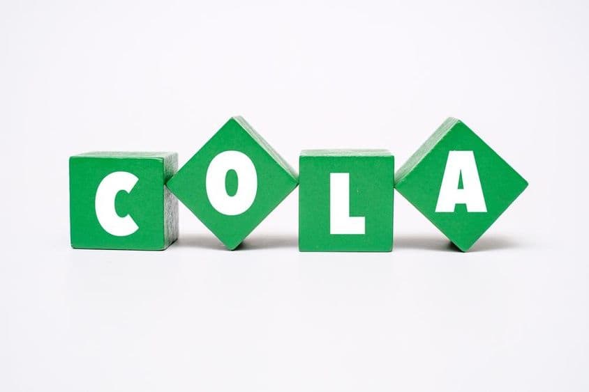 A colorful wooden block with COLA written on it.