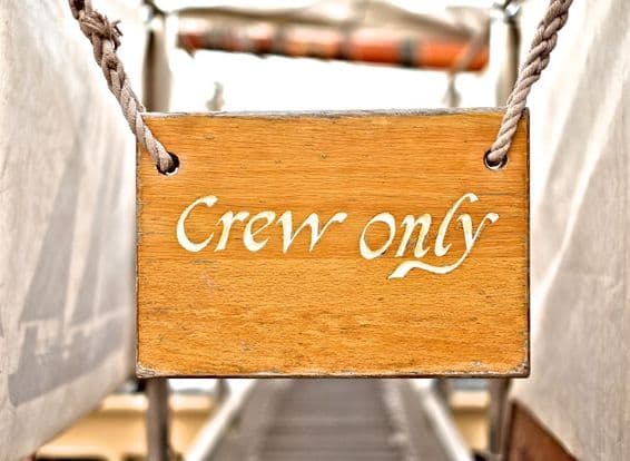 Large 'Crew only' sign above a classic sailboat crew entrance.