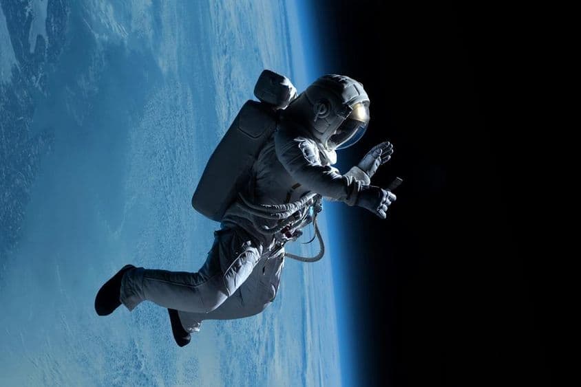 Female astronaut taking a video call on her phone during a spacewalk in deep space.