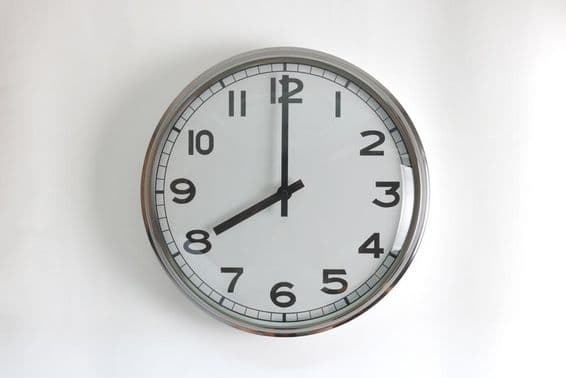 Round, stainless steel wall clock with white face.