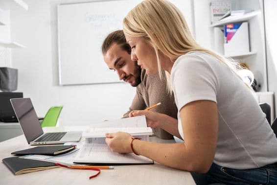 Two students reading course material in a notebook.