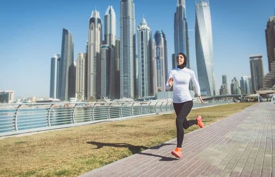 Arab woman running with skyscrapers in the background.