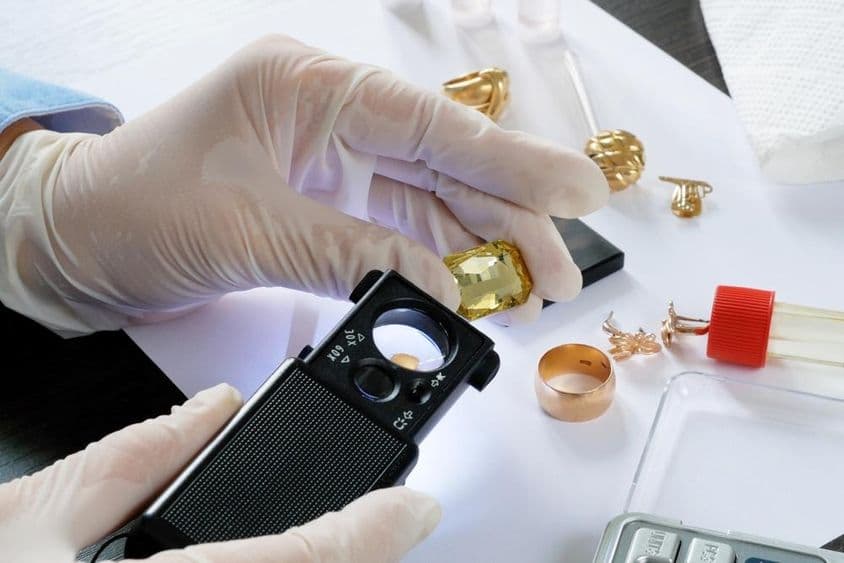 Testing old gold jewelry with reagents and touchstone.