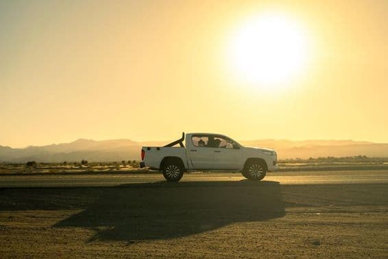 White pickup vehicle on a countryside trip, sunny day at sunset.