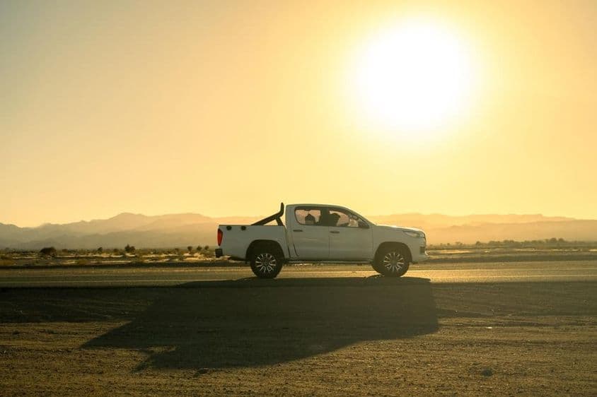White pickup vehicle on a countryside trip, sunny day at sunset.