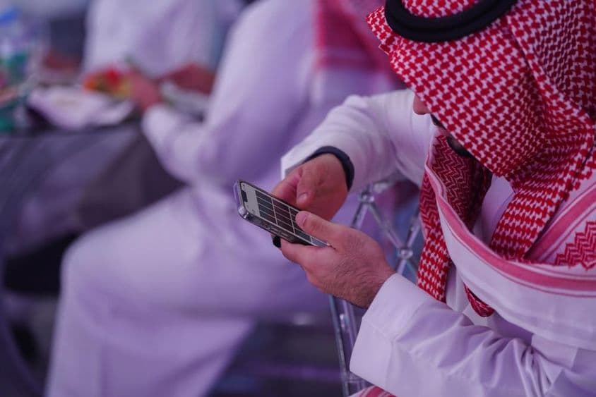 Arab man working on a mobile phone, reading or typing a message.