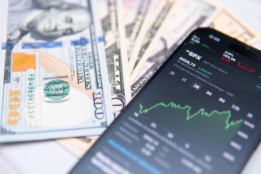 The SP500 index on smartphone screen, with US dollar backdrop.