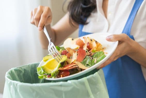 Compost from food waste, young housekeeper scraping waste with a fork.