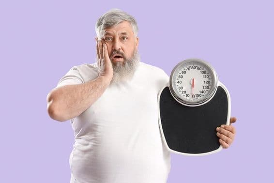 Overweight shocked elderly man with scales in hand.