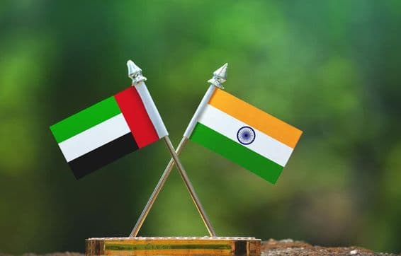 India and UAE small flags against a blurred green background.
