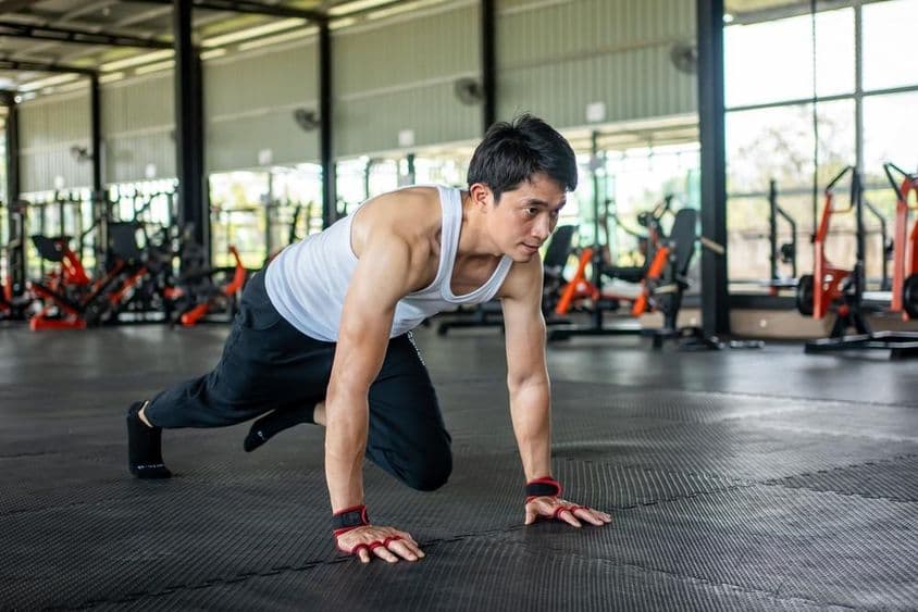 Man in gym lifting leg and moving