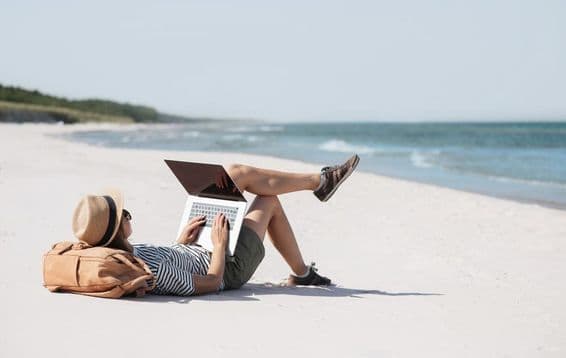 Young woman working on a laptop by the seaside doing freelance work.