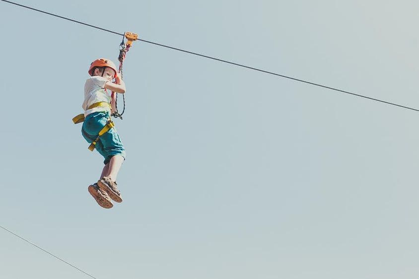 Boy climbing in an adventure park on a sunny summer day.