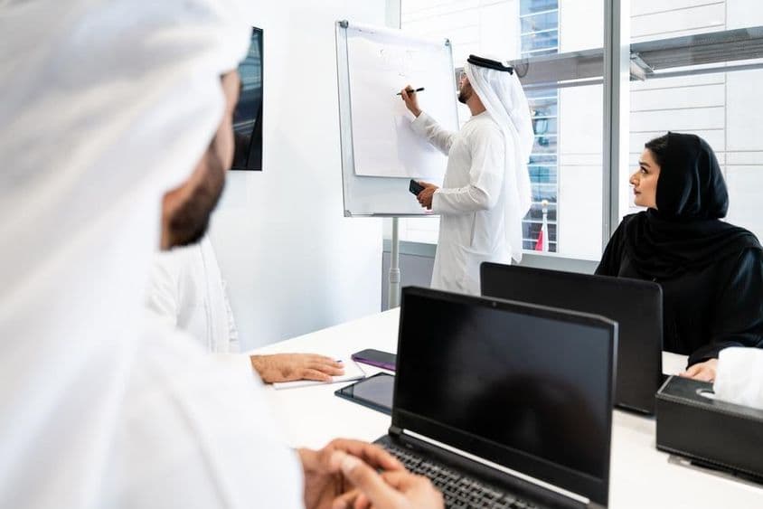A group of businessmen in traditional Emirati attire having a meeting in an office in Dubai.