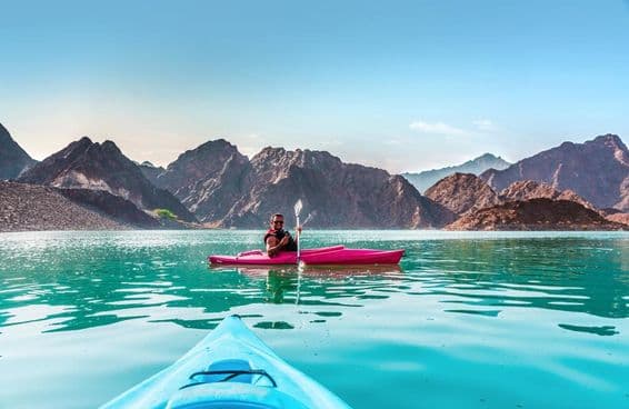 Young man kayaking in Hatta Dam, the best place for water adventure activities, in Dubai.