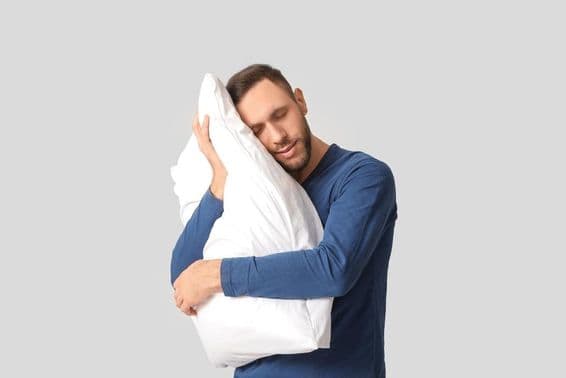 Young man in pajamas with soft pillow.