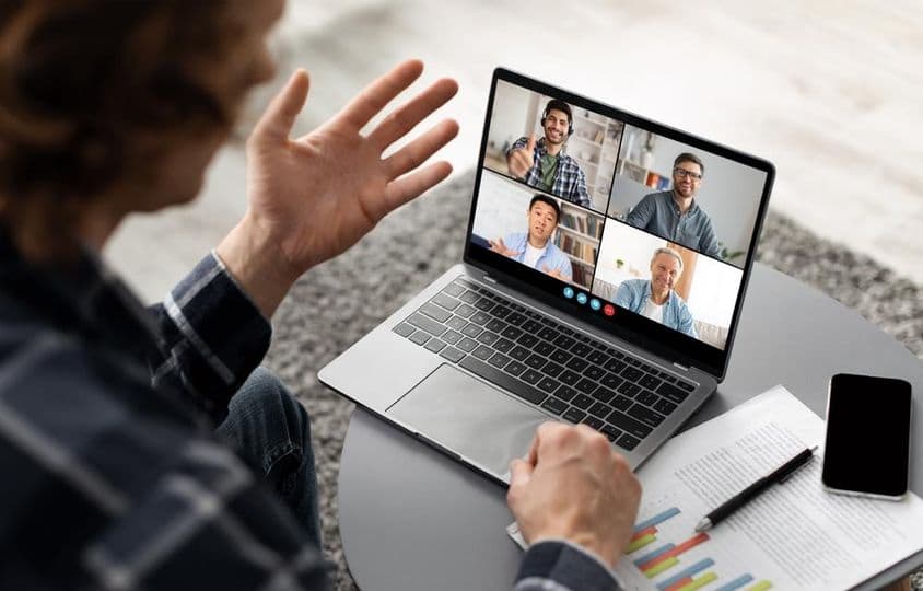 A man sitting at a desk, participating in a video conference on his laptop.
