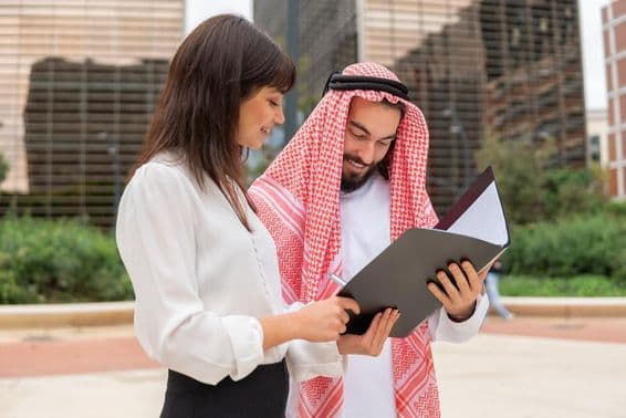Businesswoman discusses contract details with Arab male client.