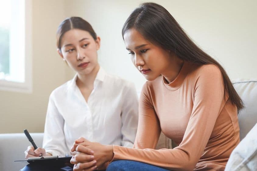 Sad Asian young woman consulting with a psychologist.