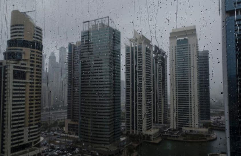 Wet window showing Dubai's modern commercial skyline.
