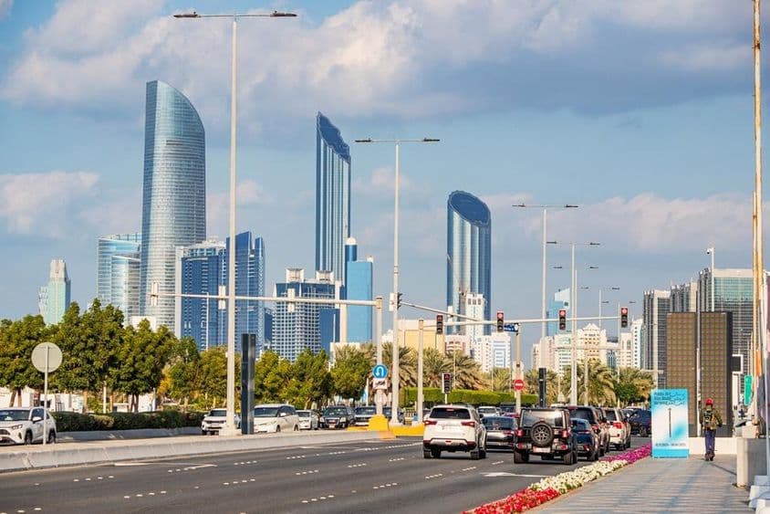 Abu Dhabi, modern skyscrapers tower in the background of the busy Corniche Road.