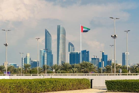 Abu Dhabi's iconic skyline with a modern skyscraper and prominently visible national flag.