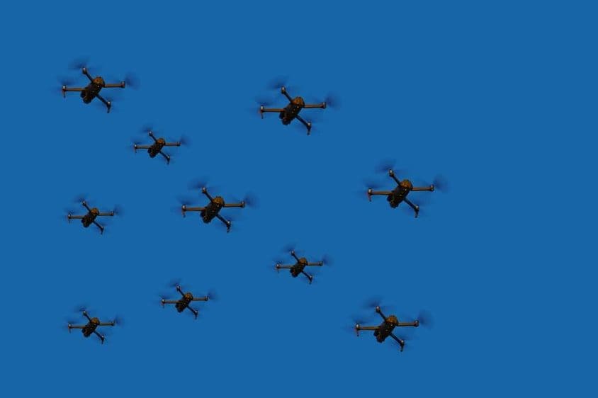 Flying drones in a fleet against a blue sky.
