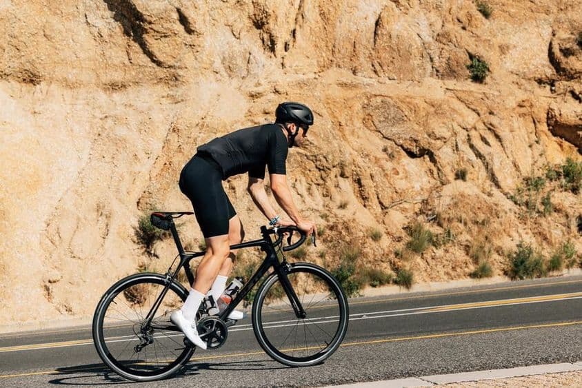 Cyclist in black sportswear engaged in intense outdoor training.