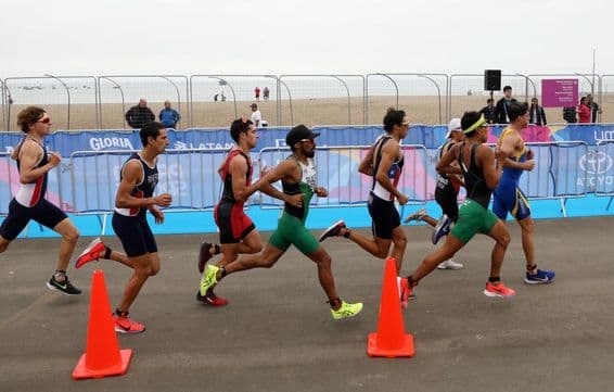 Triathlon participants running on the beach.