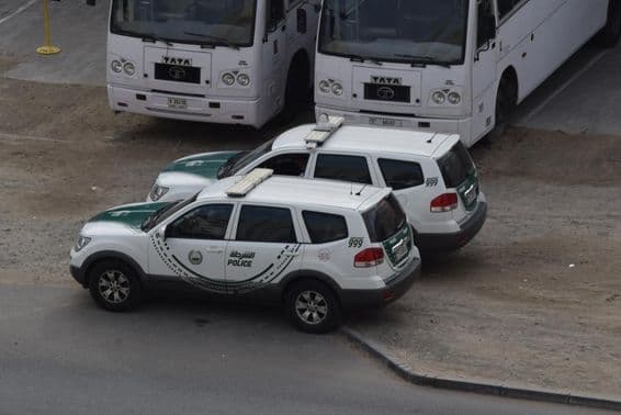 Two Dubai police cars parked in front of two buses in Al Quoz, Dubai.