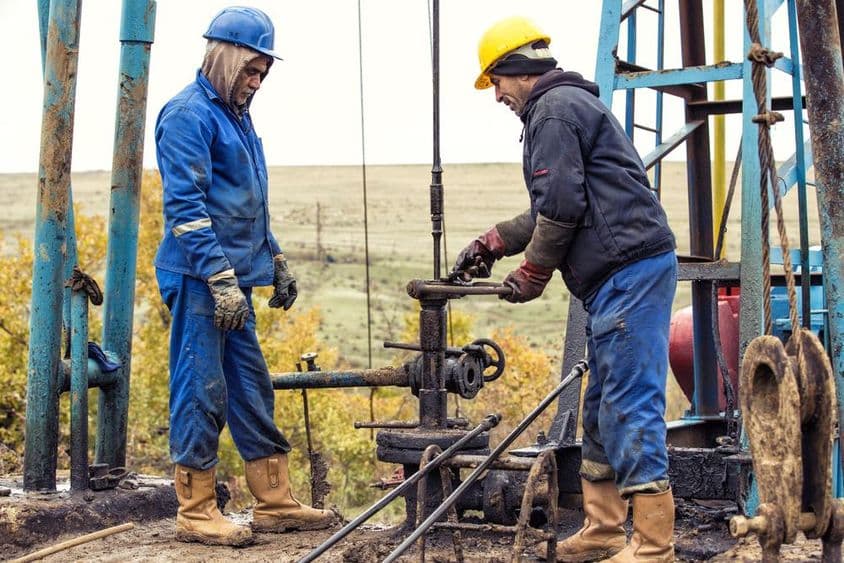 Oil workers inspecting an oil pump.