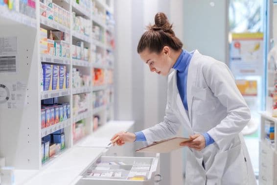 Young pharmacist checking the medicine stock in a pharmacy.