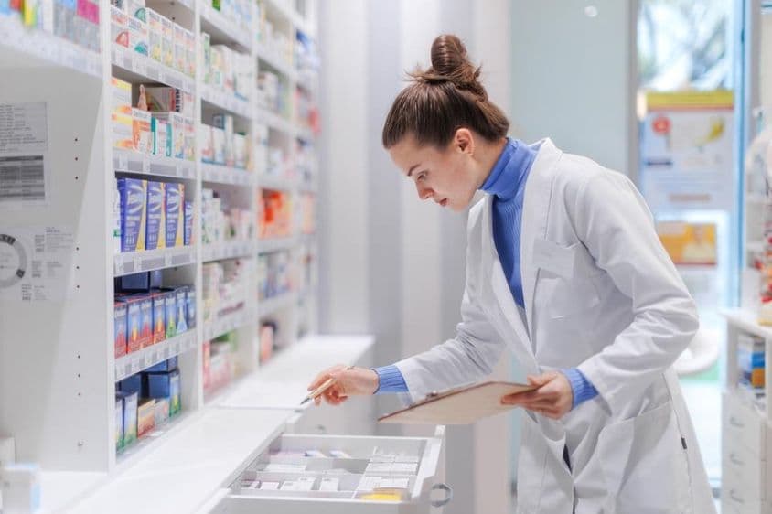 Young pharmacist checking the medicine stock in a pharmacy.