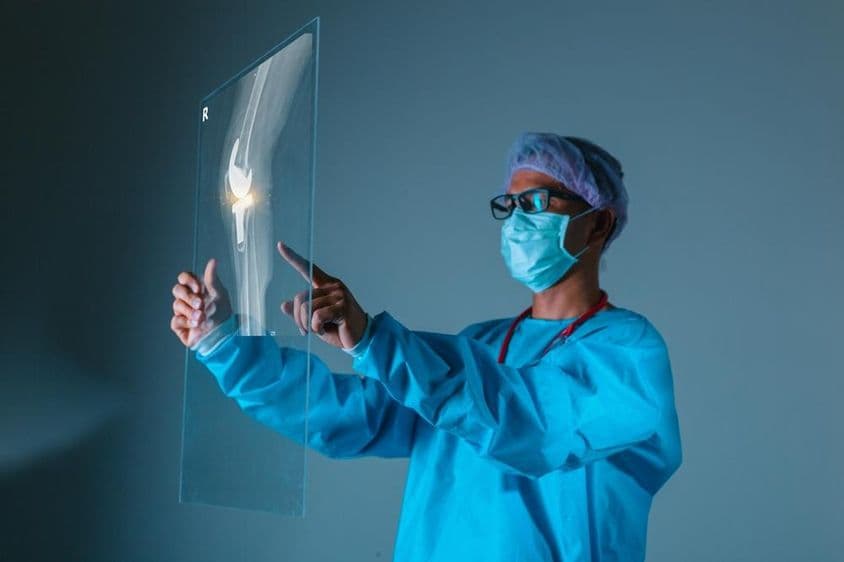 Doctor holding patient's bone X-ray image before surgery.