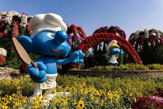 Life-sized figures of the Smurfs in colorful flowers at Dubai Miracle Garden.