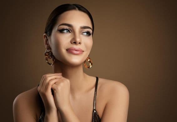 Smiling woman with smooth skin, makeup, and gold earrings.