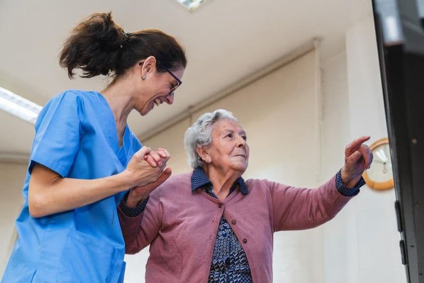 Elderly woman receiving help from a nurse in a care home.