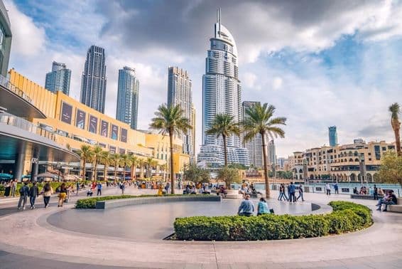 Crowds of tourists walking in the square and promenade near the entrance of Dubai Mall.