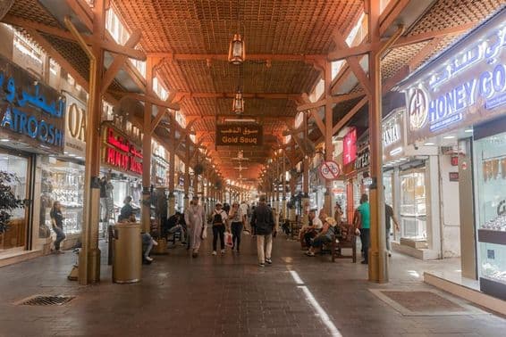 Tourists shopping and exploring Dubai's gold market.