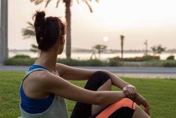 Young girl resting after yoga in a park on the Abu Dhabi Corniche.