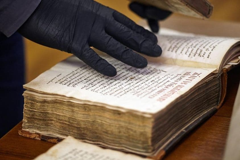 The gloved librarian holding a rare book.